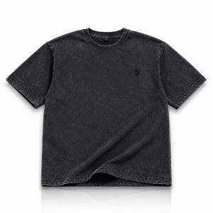 Könnte beinhalten: Ein kurzärmeliges T-Shirt in Dunkelgrau mit einem durchgehenden Acid-Wash-Effekt im Stoff. Das Oberteil verfügt über einen Rundhalsausschnitt und ein kleines, dezentes gesticktes Logo-Detail im oberen linken Brustbereich des Kleidungsstücks.
