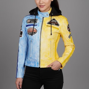 May include: A two-tone leather jacket, half light blue and half yellow, with a black hood. The jacket has several embroidered patches and a zip closure. The model is wearing black trousers.