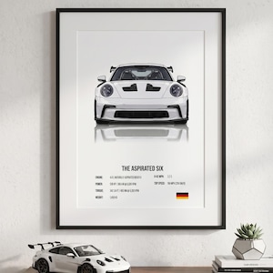 May include: A framed print featuring a white sports car with the text "THE ASPIRATED SIX". The print includes technical specifications such as engine size, horsepower, torque, and top speed. A model car sits below the print.