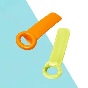 May include: Two colorful bottle openers. One is orange, the other is lime green. Each has a rectangular handle and a circular opening. The background is a mix of light blue and white.
