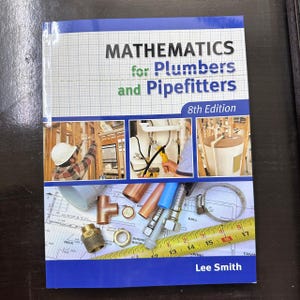 May include: A textbook titled "MATHEMATICS for Plumbers and Pipefitters, 8th Edition" with images of plumbing work and tools. The cover is blue and white, with the author's name, Lee Smith, at the bottom. Plumbing tools and blueprints are also visible.
