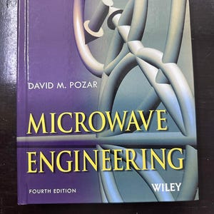 May include: A textbook titled "Microwave Engineering" by David M. Pozar. The cover is a deep purple with the title in large yellow letters. A stylized, light blue and gray graphic is featured on the right side of the cover. The Wiley logo is in the bottom right corner.