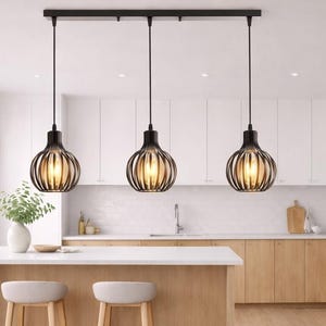 Peut inclure: Cuisine moderne avec trois suspensions noires au-dessus d'un îlot blanc. La cuisine comprend des armoires en bois clair, une crédence blanche et un sol en bois clair. Deux tabourets de bar sont placés sur l'îlot.