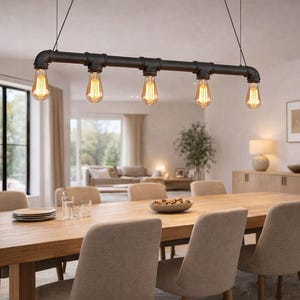Puede incluir: Una lámpara colgante negra de estilo industrial con cinco bombillas Edison sobre una mesa de comedor de madera. La lámpara está hecha de tuberías y accesorios negros. Las bombillas tienen un brillo ámbar cálido. El comedor tiene una paleta de colores neutros.