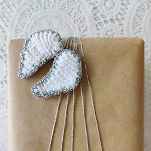 May include: A brown paper gift bag with white crocheted angel wings tied with silver string.