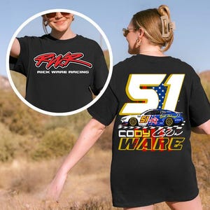 Op de afbeelding: Zwart T-shirt met de tekst "RWR Rick Ware Racing" in rood en wit op de voorkant. De achterkant van het shirt toont het nummer "51" met een sterrenpatroon, een raceauto-afbeelding en de naam "Cody Ware".
