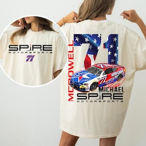May include: Cream-colored t-shirt featuring the text "SPIRE MOTORSPORTS" and the number 71 in blue and purple. The back of the shirt displays a racing car graphic with the number 71, the American flag, and the name "MICHAEL MCDOWELL".