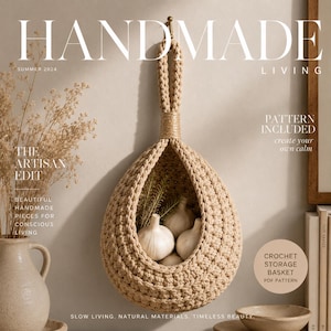May include: A beige, teardrop-shaped crochet storage basket hangs from a hook. The basket is crafted from thick, textured yarn and contains several white garlic bulbs. The text on the image reads HANDMADE LIVING, SUMMER 2024, THE ARTISAN EDIT, and CROCHET STORAGE BASKET PDF PATTERN.