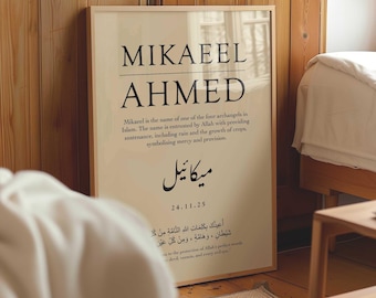 May include: A framed print with the names MIKAEEL AHMED in large black text. Below, smaller text describes Mikaeel as one of the four archangels in Islam. The print includes Arabic script and the date 24.11.25. The frame is light-colored.