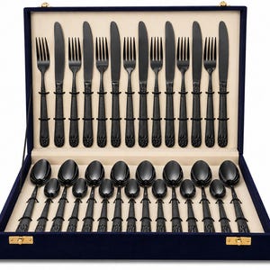 May include: A flatware set featuring matte black stainless steel utensils arranged in a navy blue velvet-lined storage case. The set includes forks, knives, and spoons with textured handles, all neatly organized in a rectangular presentation box.