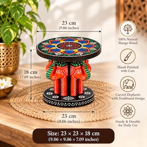 Pode incluir: Um banco redondo de madeira com um topo preto e um padrão floral colorido de mandala. A base consiste em figuras de elefantes esculpidas em laranja e verde. O banco mede 23 cm de diâmetro e 18 cm de altura, com uma base de 23 cm.