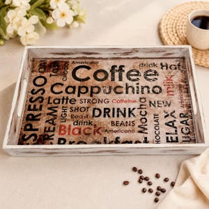 Könnte beinhalten: Ein rechteckiges Serviertablett mit einem Rahmen aus weißem, abgenutztem Holz und einem Boden, der eine Collage aus kaffeebezogenen Wörtern wie Coffee, Cappuccino, Espresso, Latte und Black in verschiedenen schwarzen, braunen und roten Schriftarten zeigt.
