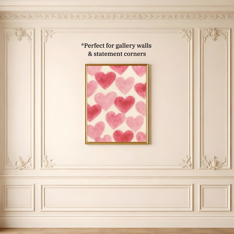 May include: A framed artwork featuring a pattern of pink and red hearts on a cream background. The artwork is in a gold frame and hangs on a white wall with decorative molding. The text "Perfect for gallery walls & statement corners" is visible.