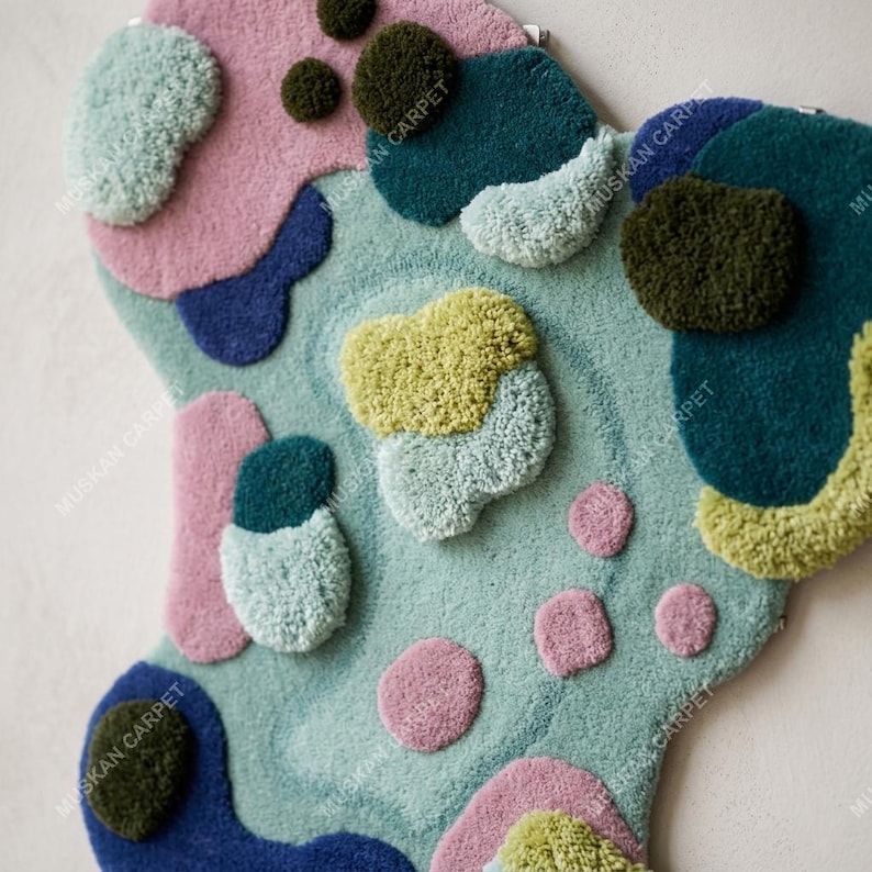 May include: A colorful, abstract rug with a unique shape. The rug features a light blue base with various shapes in pink, blue, green, and yellow. The design has a textured, tufted appearance, adding depth and visual interest to the floor covering.