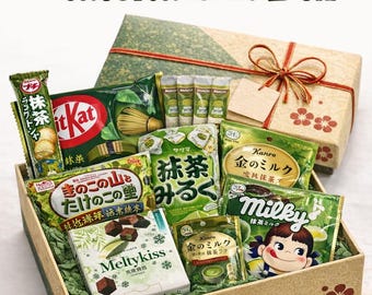 May include: A Japanese Matcha Gift Box filled with various matcha-flavored snacks and treats. The box includes Kit Kat bars, chocolate, and other packaged goods, all arranged in a decorative box with a gift box on top.