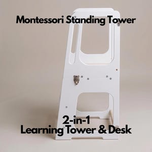 Puede incluir: Una torre de aprendizaje Montessori blanca con el texto "Montessori Standing Tower" y "2-en-1 Learning Tower & Desk". La torre tiene un marco rectangular con secciones recortadas y una pequeña plataforma de madera.