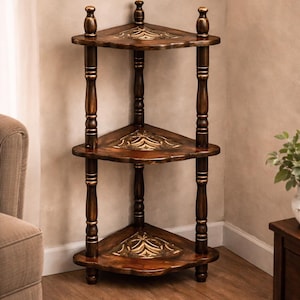 Puede incluir: Estantería esquinera de tres niveles de madera oscura con detalles dorados. Los estantes son triangulares y las patas cilíndricas con detalles decorativos. Diseñada para esquinas, es adecuada para exhibir objetos decorativos.