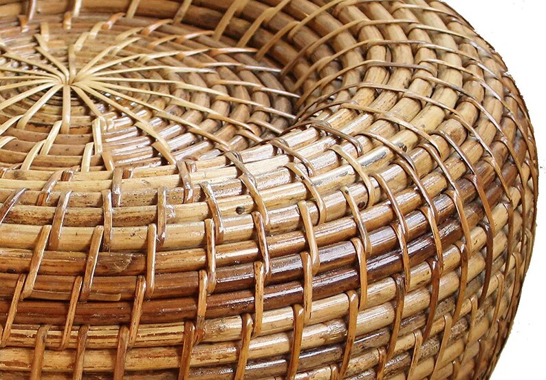 Peut inclure: Gros plan sur une chaise en rotin tress&eacute; de forme arrondie. Le mat&eacute;riau brun naturel est &eacute;troitement tiss&eacute; selon un motif de tissage en panier, cr&eacute;ant une surface textur&eacute;e. Le design de la chaise pr&eacute;sente un motif en spirale au centre.