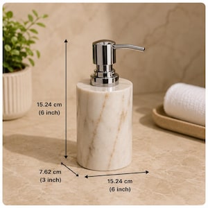 May include: A cylindrical soap dispenser made of white marble with brown veining and a polished chrome pump. The dispenser measures 15.24 cm in height, 7.62 cm in depth, and 15.24 cm in width as indicated by the visible measurement labels.