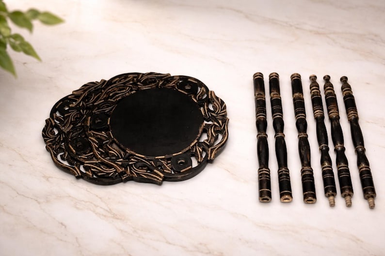 Pu&ograve; includere: Un vassoio decorativo in legno nero con un bordo intagliato e un centro scuro. Sei fusi in legno nero abbinati sono disposti a destra. Il vassoio e i fusi hanno un aspetto invecchiato e antico.