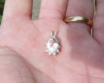 May include: A silver pendant featuring a clear oval-shaped gemstone surrounded by smaller clear gemstones.