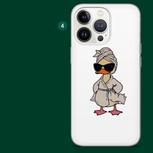 Pu&ograve; includere: Custodia per telefono bianca con un'anatra dei cartoni animati che indossa occhiali da sole, un asciugamano sulla testa e un accappatoio. L'anatra ha un becco arancione e zampe rosa. La custodia ha un modulo fotocamera con quattro lenti.