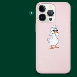 Pu&ograve; includere: Custodia per telefono rosa chiaro con un'oca dei cartoni animati che indossa occhiali da sole e un asciugamano. L'oca &egrave; bianca con zampe e becco arancioni. La custodia ha un ritaglio per la fotocamera.