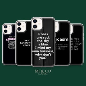 Può includere: Una collezione di custodie per telefoni nere con vari design di testo bianco. Una custodia recita: "Roses are red, the sky is blue. I mind my own business, why don't you?!" Le custodie sono di MI & CO COVERS.