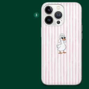 Pu&ograve; includere: Custodia per telefono bianca con un motivo a righe rosa e bianche. La custodia presenta un'anatra dei cartoni animati con occhiali da sole e un asciugamano sulla testa. La custodia ha un ritaglio per la fotocamera.