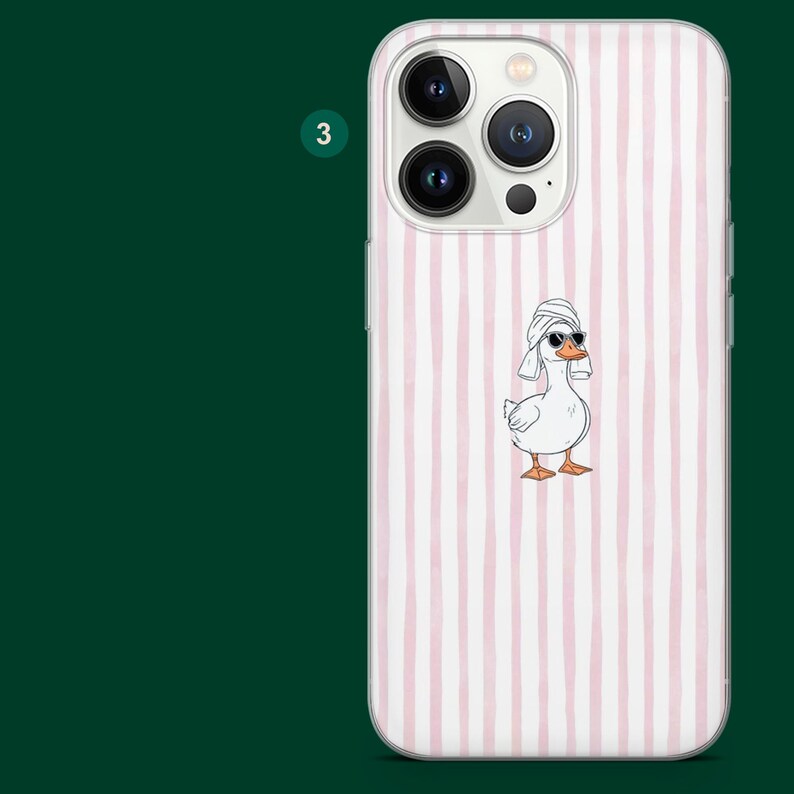 Pu&ograve; includere: Custodia per telefono bianca con un motivo a righe rosa e bianche. La custodia presenta un'anatra dei cartoni animati con occhiali da sole e un asciugamano sulla testa. La custodia ha un ritaglio per la fotocamera.