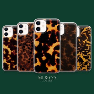 May include: Five smartphone cases arranged in a row, each featuring a distinct tortoiseshell pattern in shades of amber, brown, and black. The cases have clear edges and cutouts for camera lenses. The text MI & CO COVERS is centred below them.