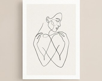 May include: A minimalist line art print featuring a woman's silhouette. The artwork is rendered in black lines on a neutral background, with the woman's arms crossed over her chest. The print is framed in a white border.