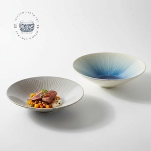 May include: Two ceramic bowls. One is a shallow, white plate with a ridged pattern, holding food. The other is a deep bowl with a blue gradient. The bowls are on a white surface. The text "Melted Earth Art Ceramic World" is in a circle.