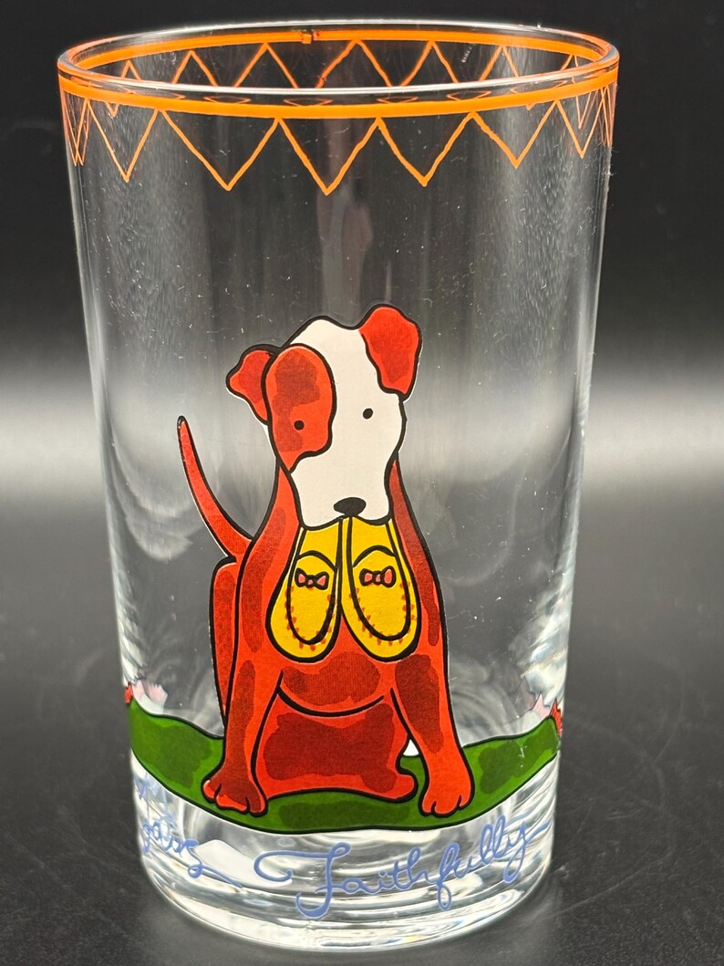 May include: Clear glass tumbler with a cartoon dog illustration. The dog is red with white markings and yellow shoes. The rim has an orange zig-zag design. The words "Faithfully" are written at the bottom of the glass.
