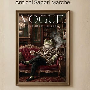 Può includere: Opera d'arte incorniciata di una copertina della rivista Vogue. Raffigura una rana con una giacca leopardata, che tiene in mano un drink e fuma. Il testo recita "VOGUE" e "Too glam to care". La scena è ambientata in una lussuosa stanza con un divano di velluto rosso e un lampadario.