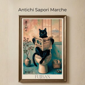 Può includere: Stampa artistica incorniciata raffigurante un gatto nero seduto su un water che legge un giornale. La stampa presenta testo giapponese e una vista del Monte Fuji sullo sfondo. L'opera d'arte è in una cornice dorata.