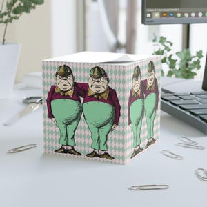 Op de afbeelding: Een vierkant notitieblok met een grillige illustratie van twee figuren in vintage kleding, tegen een roze en groen ruitpatroon. De figuren dragen bordeauxrode jassen, groene broeken en hoeden.