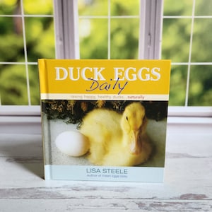 May include: A yellow book titled "Duck Eggs Daily: raising happy, healthy ducks... naturally" with a photo of a yellow duckling and a white egg on the cover. The author is Lisa Steele, author of Fresh Eggs Daily.