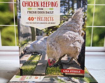 May include: A stack of three red and white paperback books titled "DIY Chicken Keeping From Fresh Eggs Daily" by Lisa Steele. The front cover features a close-up of a white chicken pecking at the ground.