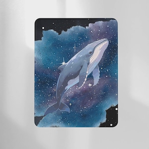 May include: A rectangular metal sign featuring a blue whale swimming through a starry galaxy. The whale is light blue with white accents, set against a backdrop of deep blues, purples, and scattered stars. The sign has a black border.