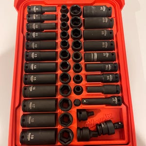 May include: A red toolbox with a clear lid, filled with a set of black impact sockets and extensions. The sockets are labeled with sizes in inches, ranging from 3/8" to 3/4". The brand name "QUINN" is visible on the sockets.