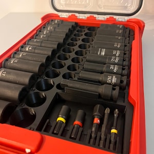 Puede incluir: Una caja de herramientas roja con tapa transparente, llena de llaves de vaso y puntas negras. Las llaves de vaso est&aacute;n dispuestas en filas, con tama&ntilde;os en pulgadas. Las puntas tienen bandas de colores. La caja est&aacute; dise&ntilde;ada para la organizaci&oacute;n y el f&aacute;cil acceso.