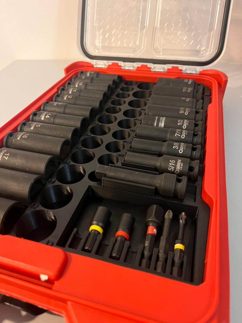Puede incluir: Una caja de herramientas roja con tapa transparente, llena de llaves de vaso y puntas negras. Las llaves de vaso est&aacute;n dispuestas en filas, con tama&ntilde;os en pulgadas. Las puntas tienen bandas de colores. La caja est&aacute; dise&ntilde;ada para la organizaci&oacute;n y el f&aacute;cil acceso.