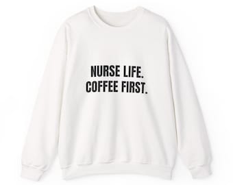 Op de afbeelding: Een witte crew neck sweatshirt met de zwarte tekst "NURSE LIFE. COFFEE FIRST.". De trui met lange mouwen heeft een eenvoudig, casual ontwerp, perfect voor dagelijks gebruik.