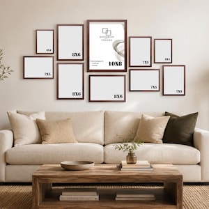 May include: A collection of framed art in various sizes, including 20x15cm and 18x13cm frames, displayed above a beige sofa. The frames have dark brown borders and white matting. The central frame is 25x20cm and features the text "Emporium Frames".