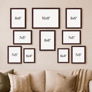 May include: A gallery wall arrangement of eleven dark brown picture frames with white matting, featuring sizes 20x15 cm, 25x20 cm, 18x13 cm, and 15x10 cm printed on the white inserts, displayed in a symmetrical grid layout on a plain wall above a sofa.