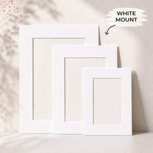 May include: Three rectangular white picture mounts of varying sizes arranged in a cascading formation. Each mount features a clean-cut central rectangular aperture for framing artwork. The text WHITE MOUNT is printed with a black arrow pointing down.