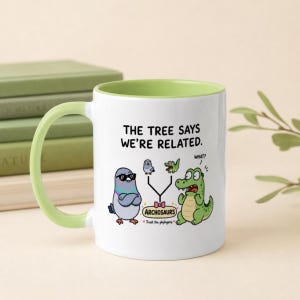 Peut inclure: Un mug en céramique blanc avec une anse et un intérieur vert clair. Le mug présente une illustration de dessin animé d'un pigeon et d'un crocodile avec le texte "THE TREE SAYS WE'RE RELATED." et "ARCHOSAURS Trust the phylogeny." et une bulle "WHAT?".