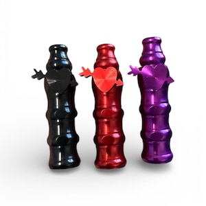 Puede incluir: Tres tapones decorativos para botellas en negro, rojo y morado. Cada tapón tiene un corazón con una flecha atravesándolo. Los tapones tienen un diseño acanalado y son de metal brillante.