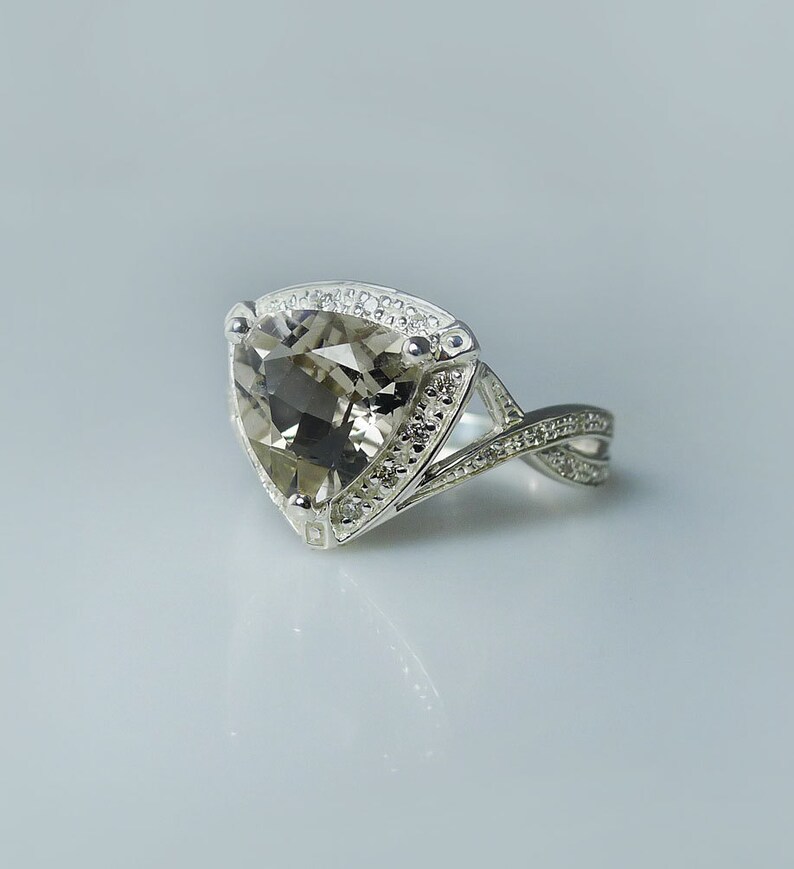 K&ouml;nnte beinhalten: Ein silberner Ring mit einem gro&szlig;en, dreieckigen, facettierten, rauchquarzfarbenen Edelstein. Der Ring hat ein zartes, gedrehtes Band.